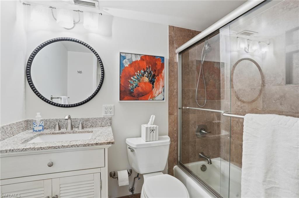 5 Bluebill Avenue, Unit 301 Naples, FL 34108 - Photo 22 of 48 a bathroom with a granite countertop toilet sink and mirror
