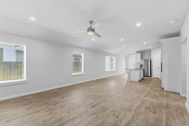a view of empty room with wooden floor and windows