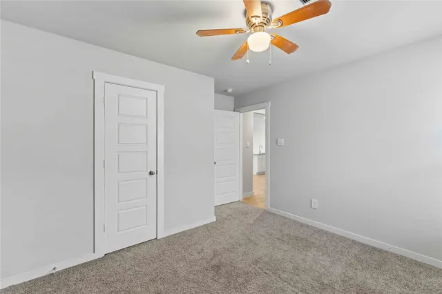 an empty room with closet and a chandelier fan