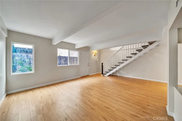 a view of an empty room with wooden floor and stairs