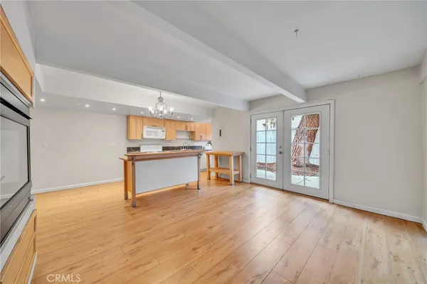 a view of an empty room with kitchen and window