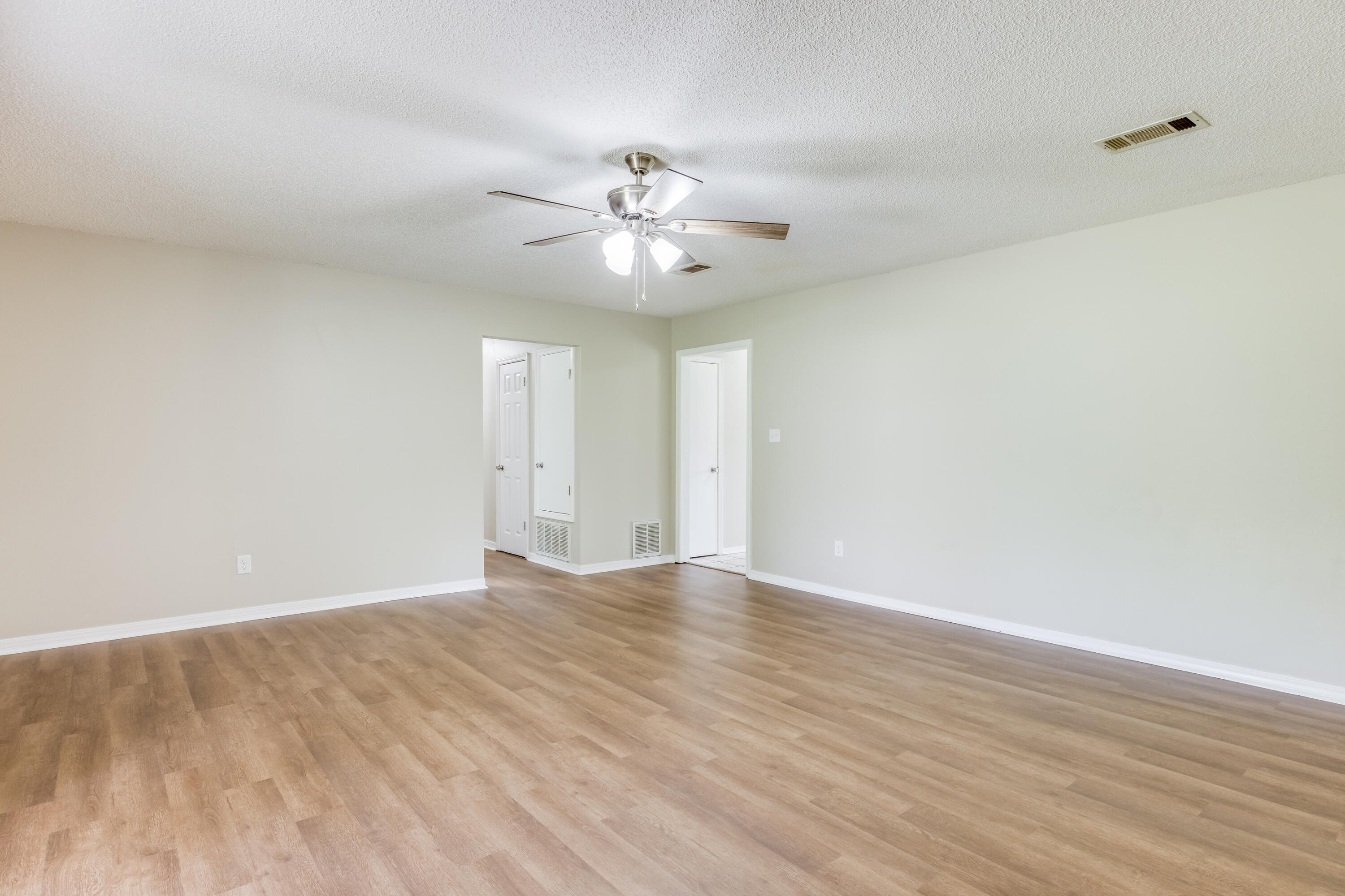 5892 Jack Stokes Road Baker, FL 32531 - Photo 10 of 49 a view of an empty room with chandelier fan and wooden floor