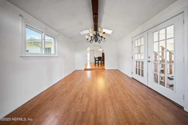 a big room with wooden floor a chandelier fan and windows