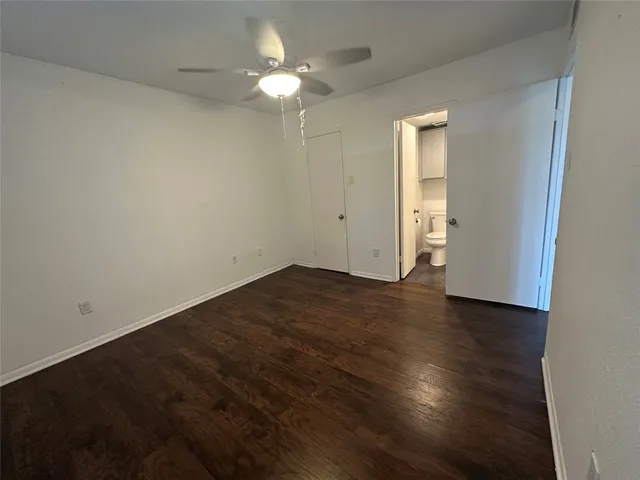 an empty room with wooden floor and fan
