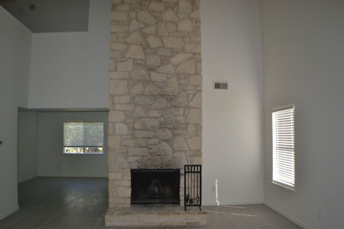 4506 Adelphi Lane Austin, TX 78727 - Photo 6 of 13 Unfurnished living room with a high ceiling, a fireplace, and tile patterned floors