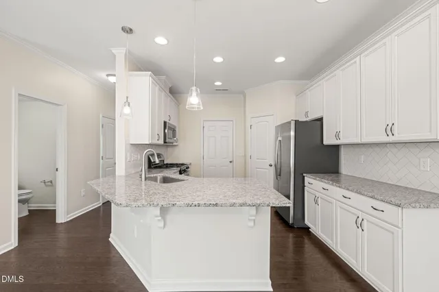 a kitchen with a refrigerator a sink and wooden floor