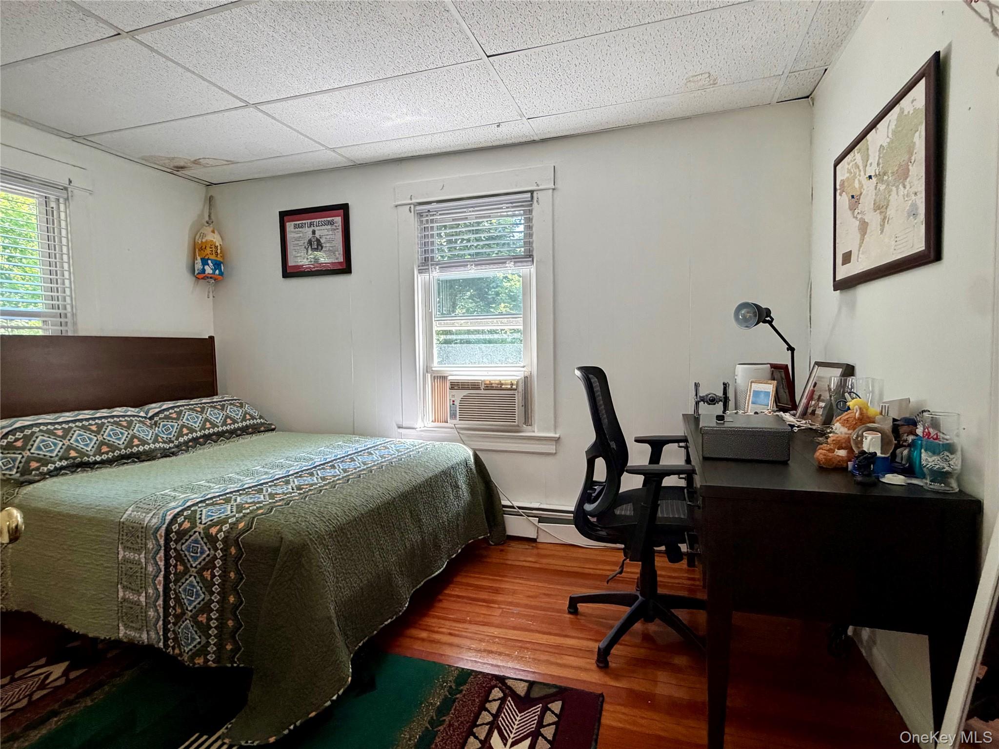 149 Fort Salonga Road Northport, NY 11768 - Photo 4 of 23 Room featuring wood-finish flooring, two windows with blinds, a paneled ceiling, and white wall finishes