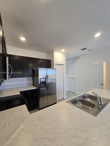 a kitchen with stainless steel appliances kitchen island granite countertop a refrigerator and a sink