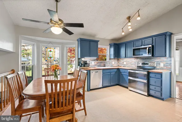 a kitchen with stainless steel appliances granite countertop a stove a sink dishwasher a dining table and chairs with wooden floor