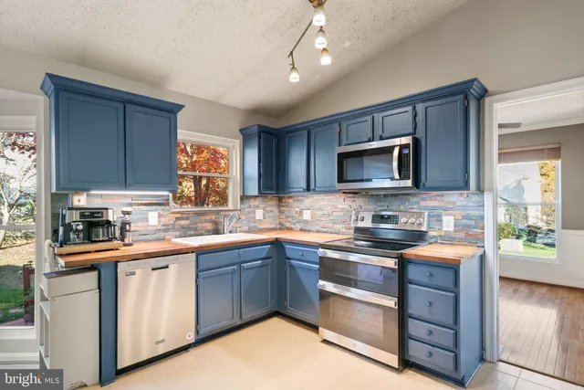 a kitchen with stainless steel appliances granite countertop a stove top oven a sink dishwasher a dining table and chairs with wooden floor