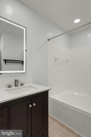 a bathroom with a bathtub sink vanity and mirror