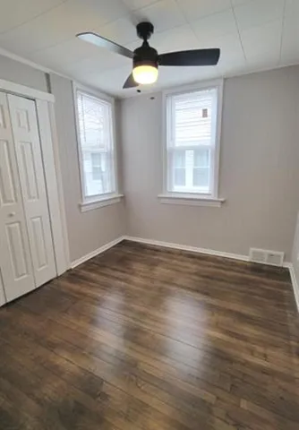 a view of empty room with wooden floor and fan