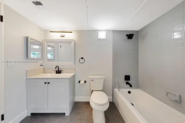 a bathroom with a toilet a sink a mirror a bathtub and vanity