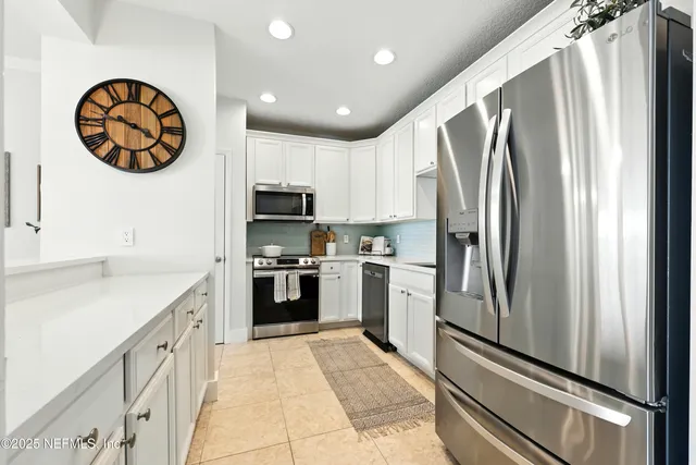 a kitchen with white cabinets and stainless steel appliances