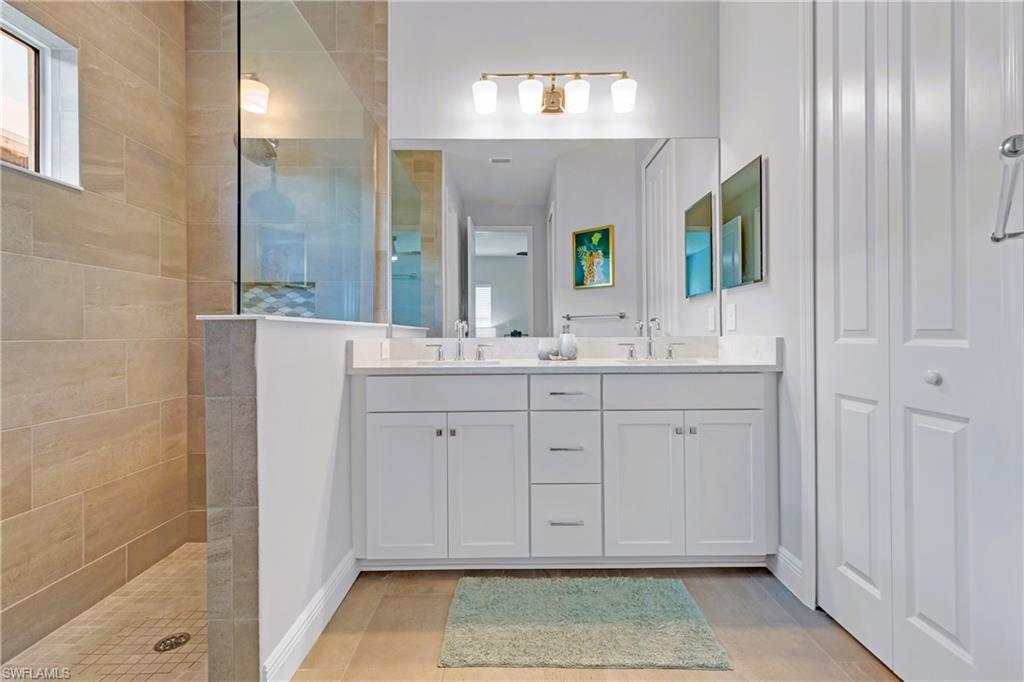 4664 Centaurus Circle Naples, FL 34120 - Photo 19 of 37 a spacious bathroom with a double vanity sink a mirror and a shower