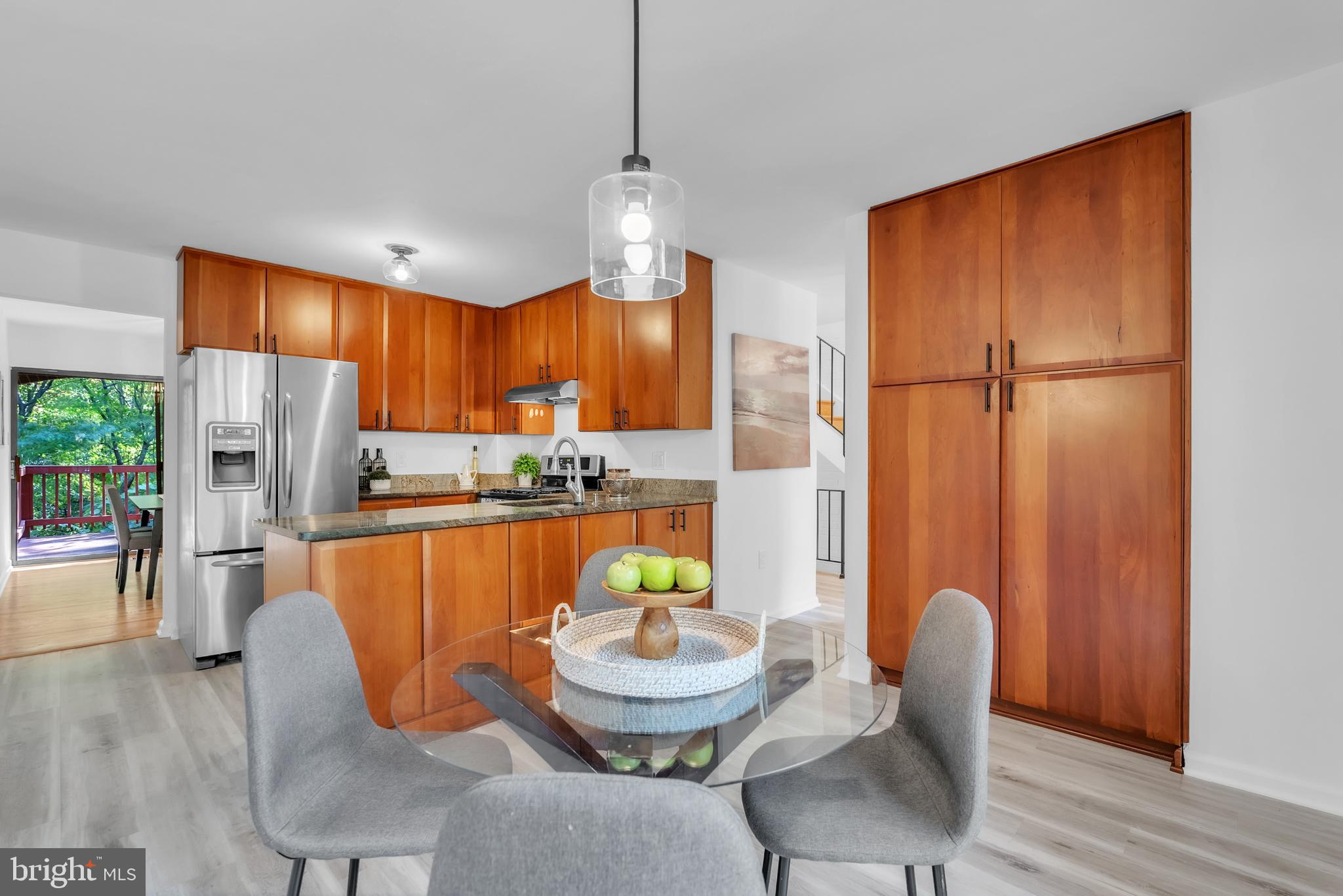 8074 Inverness Ridge Road Potomac, MD 20854 - Photo 14 of 41 a kitchen with stainless steel appliances granite countertop a refrigerator a microwave oven a dining table and chairs with wooden floor