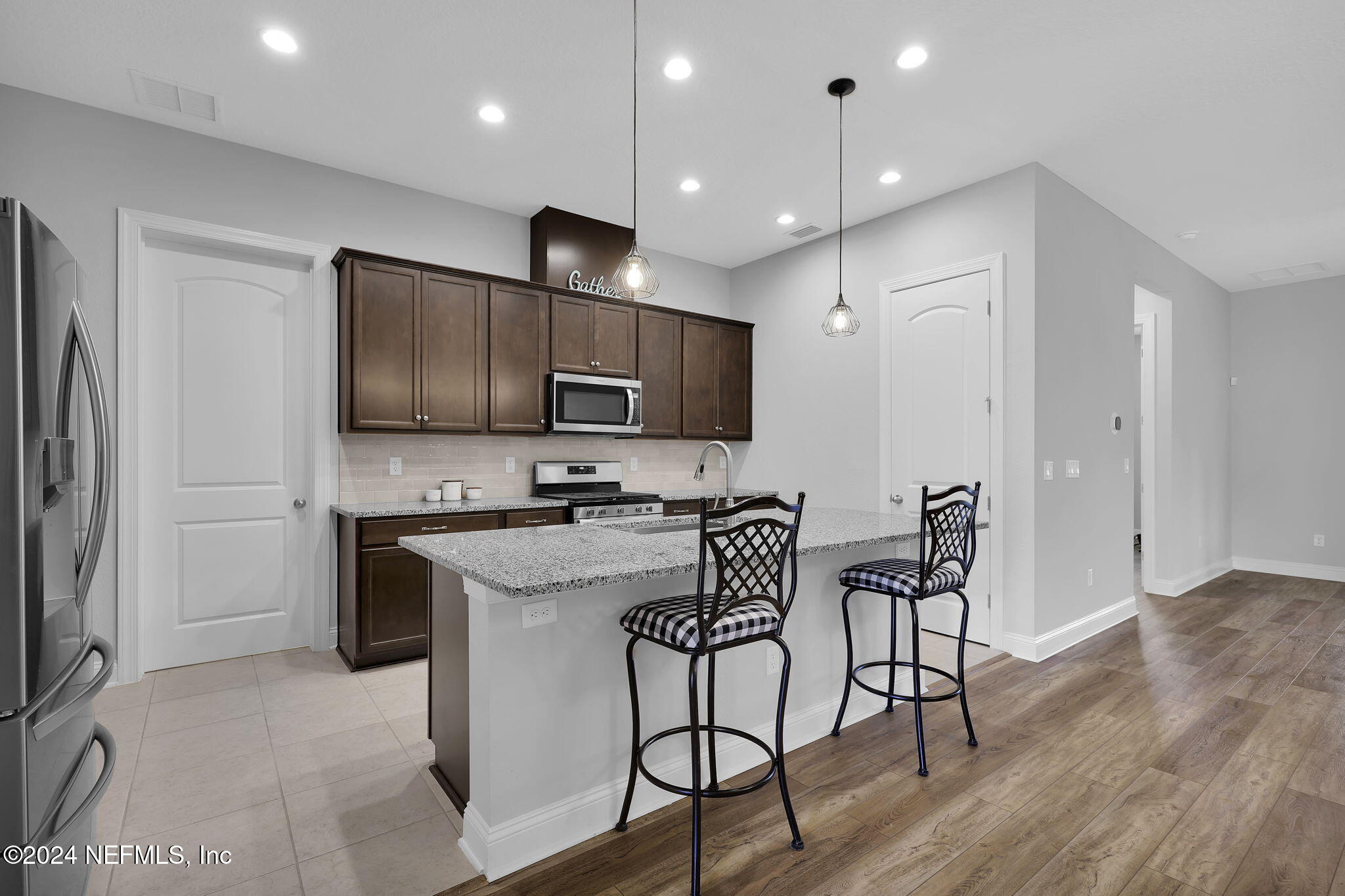 217 Liberty Bell Road Ponte Vedra, FL 32081 - Photo 6 of 50 a kitchen with stainless steel appliances a microwave a stove a sink dishwasher a refrigerator with a dining table and chairs with wooden floor