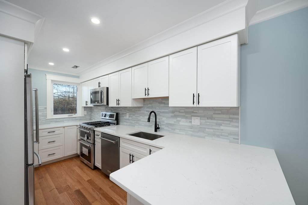 a kitchen with white cabinets a sink stove and refrigerator