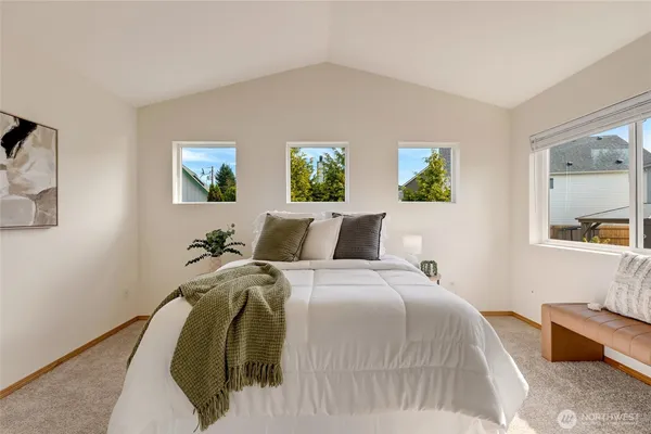 a bed room with a bed a painting on the wall and a window