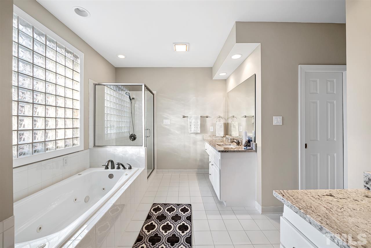 7605 Rainwater Road Raleigh, NC 27615 - Photo 18 of 30 a bathroom with a tub a sink and a large mirror