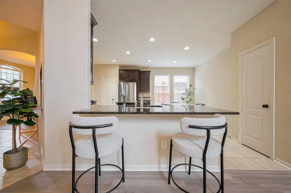 a kitchen with stainless steel appliances granite countertop a stove top oven a sink dishwasher a dining table and chairs with wooden floor