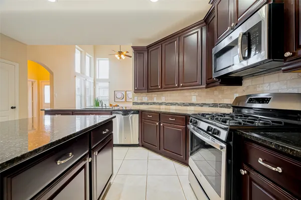 a kitchen with stainless steel appliances kitchen island granite countertop a stove a refrigerator a sink a dining table and chairs