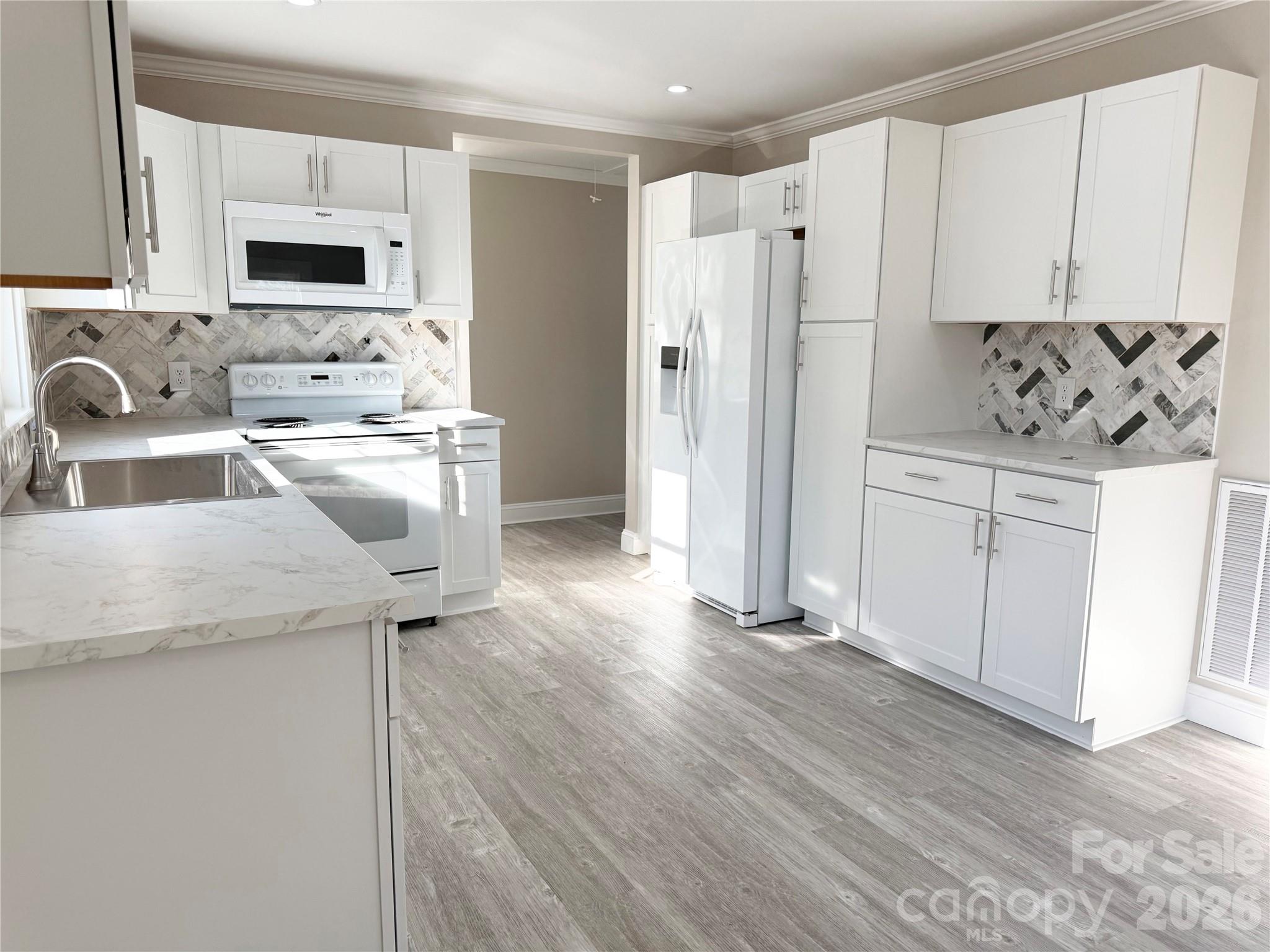 438 Pop Davis Road Taylorsville, NC 28681 - Photo 4 of 31 a kitchen with stainless steel appliances granite countertop a refrigerator a stove and white cabinets with wooden floor