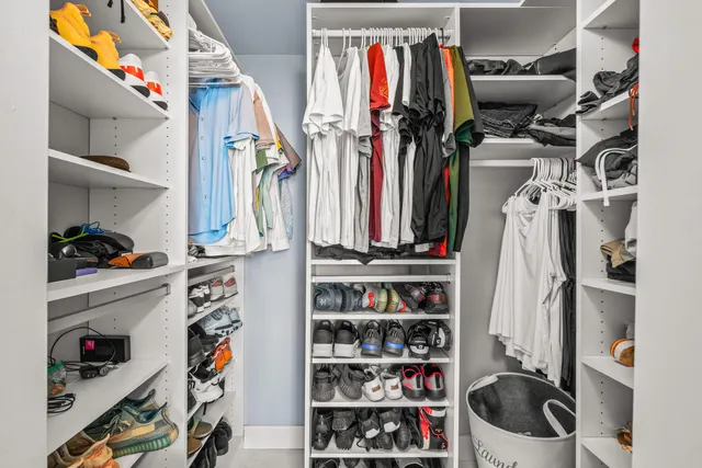 a view of walk in closet with clothes and shoes
