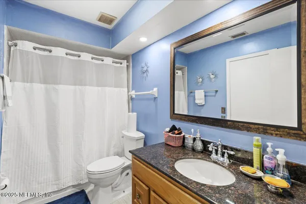 a bathroom with a granite countertop sink vanity mirror and toilet