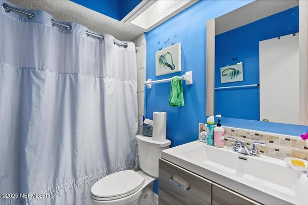 a bathroom with a sink a toilet and shower curtain