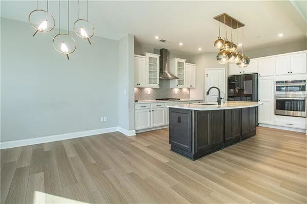 a kitchen with stainless steel appliances granite countertop a sink cabinets and wooden floor