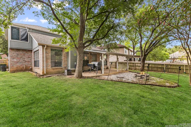 a view of a house with a yard deck and a large tree