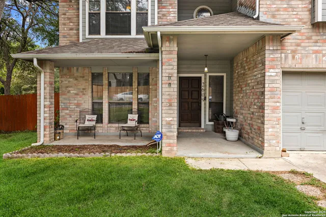 front view of a brick house with a yard and a large tree