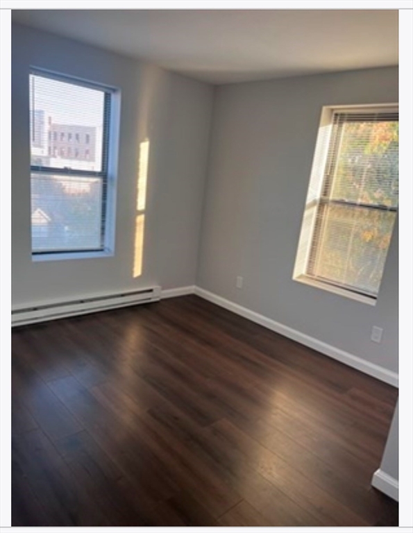 56 Johnson Street, Unit 16 Lynn, MA 01902 - Photo 4 of 5 an empty room with wooden floor and windows