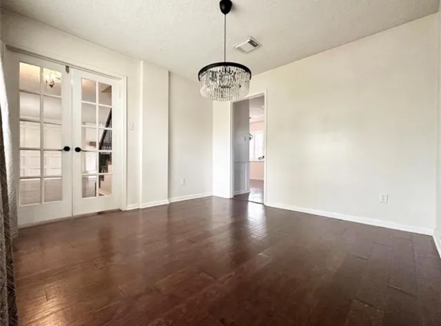 a view of a room with wooden floor chandelier and windows