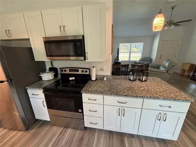 a kitchen with stainless steel appliances granite countertop a stove a sink and a microwave