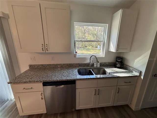 a kitchen with stainless steel appliances granite countertop a sink dishwasher window and cabinets