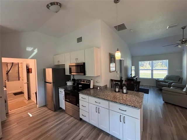 a kitchen with granite countertop a refrigerator stove top oven and sink
