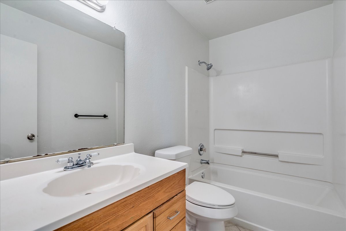 100 Easy Street Hutto, TX 78634 - Photo 22 of 36 A well-maintained bathroom provides a single vanity, mirror, and bathtub with an integrated shower.
