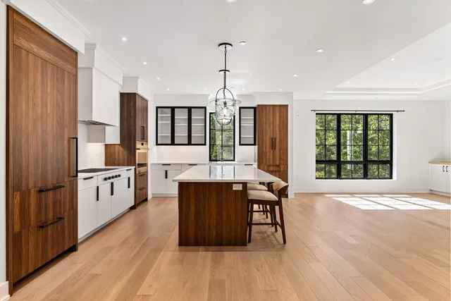 a kitchen with stainless steel appliances granite countertop a stove a sink dishwasher a refrigerator and a dining table with wooden floor