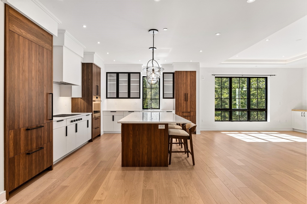 148 Weston Road, Unit 207 Wellesley, MA 02482 - Photo 8 of 25 a kitchen with stainless steel appliances granite countertop a stove a sink dishwasher a refrigerator and a dining table with wooden floor