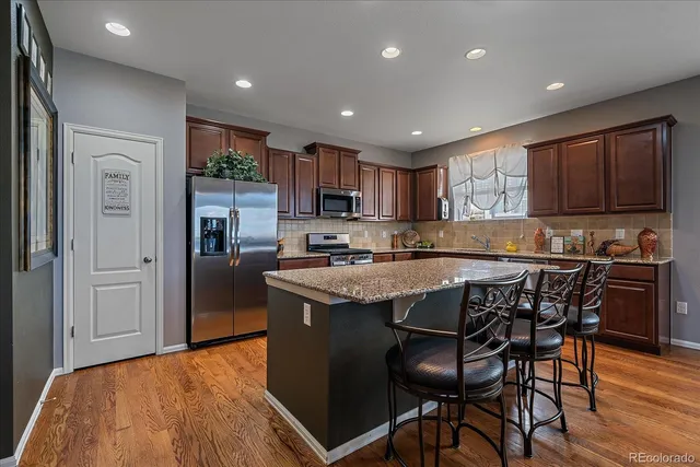 a kitchen with stainless steel appliances granite countertop a table chairs sink refrigerator and cabinets