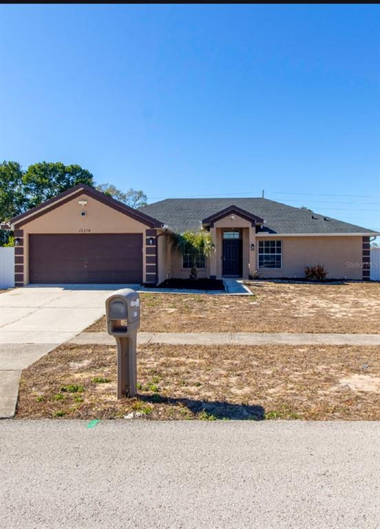 12374 Corrine Avenue Spring Hill, FL 34609 - Photo 2 of 28 a front view of a house with a garden