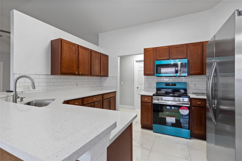 12374 Corrine Avenue Spring Hill, FL 34609 - Photo 26 of 28 a kitchen with stainless steel appliances granite countertop a sink stove and refrigerator