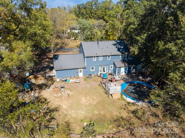 an aerial view of a house with swimming pool and large trees