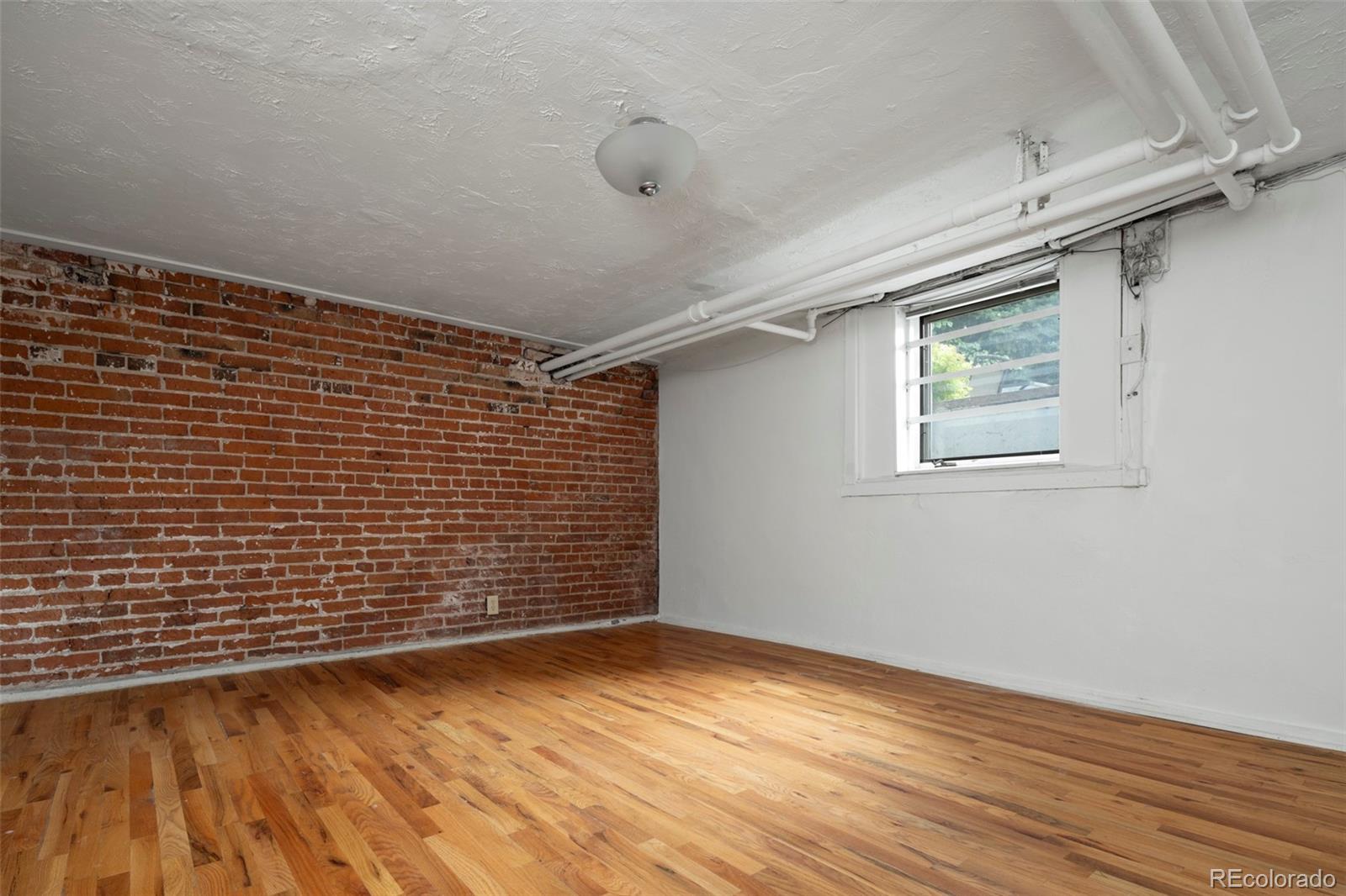 707 Corona Street Denver, CO 80218 - Photo 31 of 46 a view of an empty room with wooden floor and a window