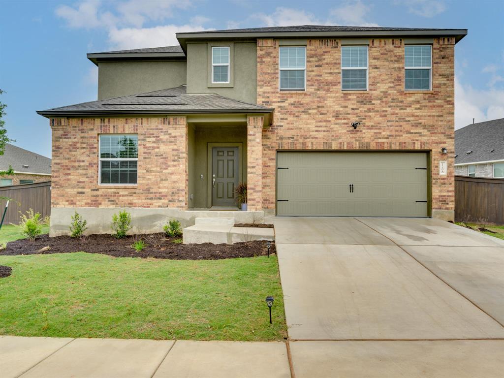 1208 Sweetspire Street Leander, TX 78641 - Photo 34 of 36 Brick and stucco facade featuring a two-car garage with a light-toned door