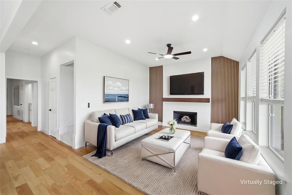 2104 Old McGarrah Road McKinney, TX 75072 - Photo 23 of 35 Living area featuring wood-finish flooring, a contemporary fireplace with a white mantel, and a ceiling fan with integrated lighting