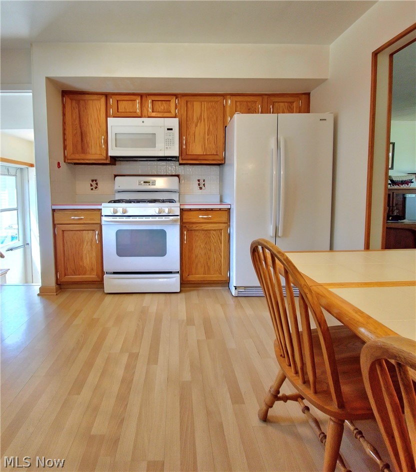 39195 Johnnycake Ridge Road Willoughby, OH 44094 - Photo 4 of 22 Kitchen featuring light wood-style floors, white appliances, and tasteful backsplash