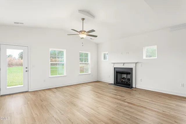 an empty room with windows fireplace and wooden floor